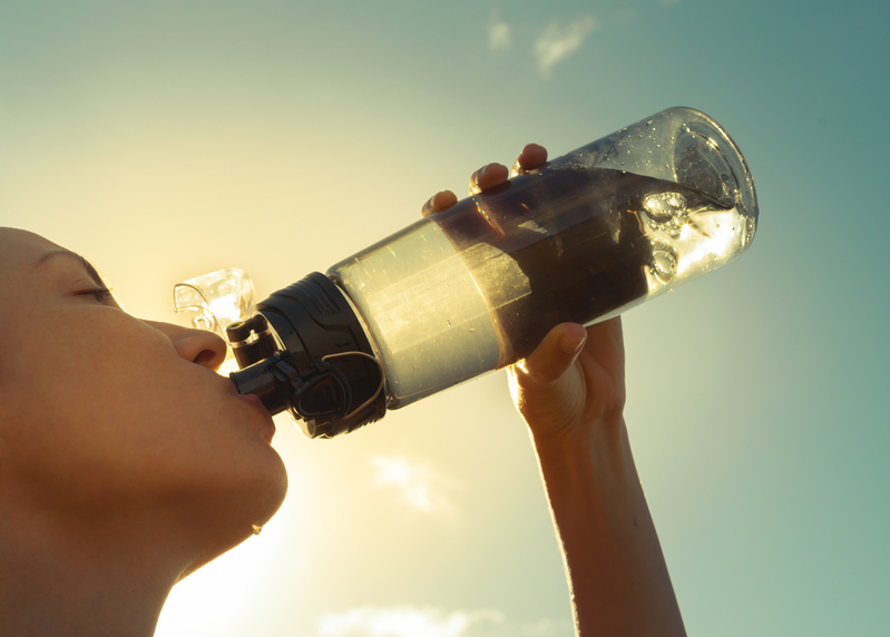 woman drinking bottle of water outside